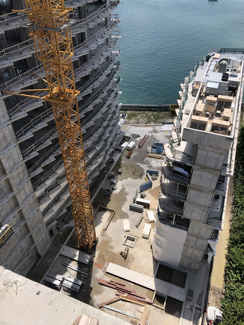 Looking down the concrete frame of Monad Terrace under construction, tower crane and Biscayne Bay below